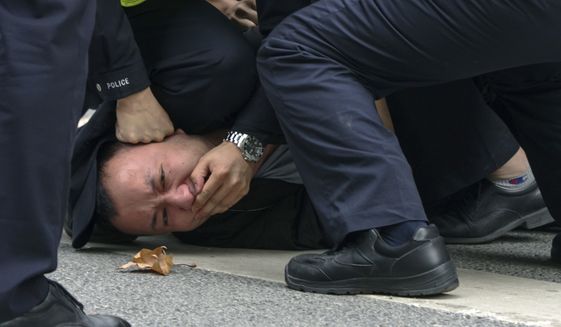 In this photo taken on Sunday, Nov. 27, 2022, policemen pin down and arrest a protester during a protest on a street in Shanghai, China. Authorities eased anti-virus rules in scattered areas but affirmed China&#39;s severe &quot;zero-COVID&quot; strategy Monday after crowds demanded President Xi Jinping resign during protests against controls that confine millions of people to their homes. (AP Photo)