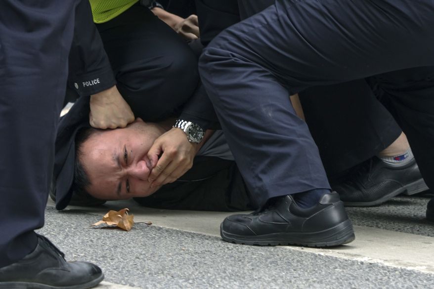 In this photo taken on Sunday, Nov. 27, 2022, policemen pin down and arrest a protester during a protest on a street in Shanghai, China. Authorities eased anti-virus rules in scattered areas but affirmed China&#x27;s severe &quot;zero-COVID&quot; strategy Monday after crowds demanded President Xi Jinping resign during protests against controls that confine millions of people to their homes. (AP Photo)