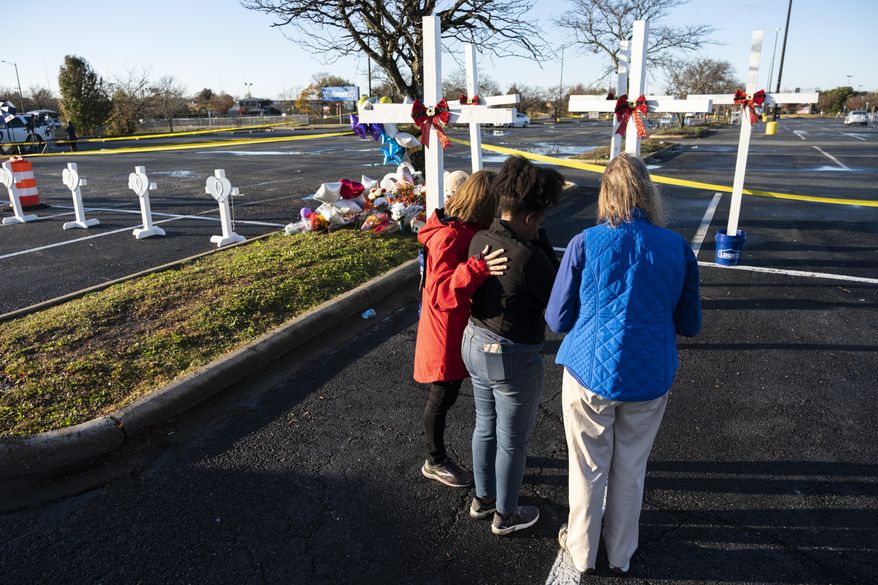 Sheree Perry of Virginia Beach, center, prays with chaplains at a memorial on Friday, Nov. 25, 2022 , for the six killed in a Chesapeake, Va., Walmart mass shooting earlier in the week. (Billy Schuerman/The Virginian-Pilot via AP)