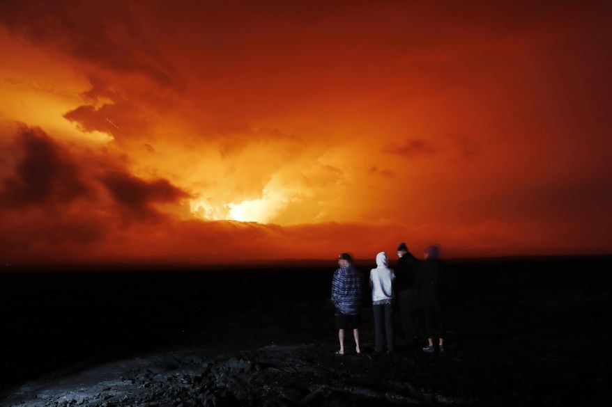 People watch the eruption of Mauna Loa, Monday, Nov. 28, 2022, near Hilo, Hawaii. Mauna Loa, the world&#x27;s largest active volcano erupted Monday for the first time in 38 years. (AP Photo/Marco Garcia)