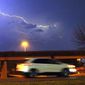 A vehicle races along a Jackson, Miss., street as lightning streaks across the sky, Tuesday evening, Nov. 29, 2022. Area residents were provided a light show as severe weather accompanied by some potential twisters affected parts of Louisiana and Mississippi. (AP Photo/Rogelio V. Solis)