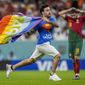 A pitch invader runs across the field with a rainbow flag during the World Cup group H soccer match between Portugal and Uruguay, at the Lusail Stadium in Lusail, Qatar, Monday, Nov. 28, 2022. (AP Photo/Abbie Parr, File)