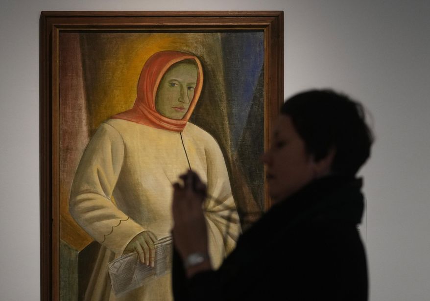 A woman takes photos next to the painting by Ukrainian artist Vasyl Sedliar called &#x27;Portrait of Oksana Pavlenko&#x27; during the inauguration of the Ukraine art exposition at the Thyssen-Bornemisza museum in Madrid, Spain, Monday, Nov. 28, 2022. Against a backdrop of Russian attacks, border closures and a nail-biting journey across Europe, Madrid&#x27;s Thyssen-Bornemisza National Museum has teamed up with Kyiv&#x27;s National Art Museum of Ukraine to secretly bring dozens of Ukrainian 20th century avant garde artworks by road to the Spanish capital for a unique exhibition and statement of support for the war-torn country. (AP Photo/Paul White)