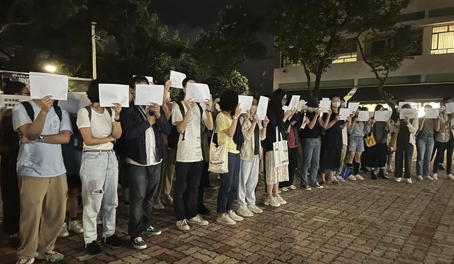 Protesters hold up blank white papers during a commemoration for victims of a recent Urumqi deadly fire at the Chinese University of Hong Kong in Hong Kong, Monday, Nov. 28, 2022. Students in Hong Kong chanted “oppose dictatorship” in a protest against China’s anti-virus controls after crowds in mainland cities called for President Xi Jinping to resign in the biggest show of opposition to the ruling Communist Party in decades. (AP Photo/Kanis Leung)