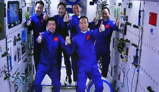In this photo released by Xinhua News Agency, an image captured off a screen at the Jiuquan Satellite Launch Center in northwest China shows the Shenzhou-15 and Shenzhou-14 crew taking a group picture with their thumbs up after a historic gathering in space on Wednesday, Nov. 30, 2022. Three Chinese astronauts docked early Wednesday with their country&#39;s space station, where they will overlap for several days with the three-member crew already onboard and expand the facility to its maximum size. (Guo Zhongzheng/Xinhua via AP)