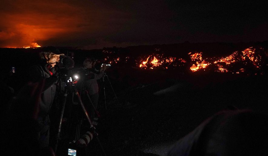 A journalist records images of lava from the Mauna Loa volcano as it erupts Wednesday, Nov. 30, 2022, near Hilo, Hawaii. (AP Photo/Gregory Bull)