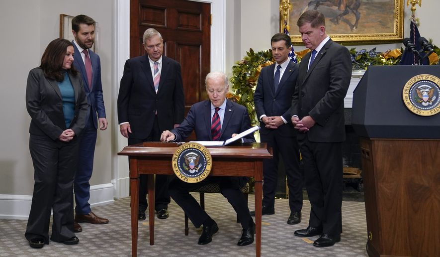 President Joe Biden signs H.J.Res.100, a bill that aims to avert a freight rail strike, in the Roosevelt Room at the White House, Friday, Dec. 2, 2022, in Washington. Biden is joined by from left, Celeste Drake, Made in America Director at the Office of Management and Budget, National Economic Council director Brian Deese, Agriculture Secretary Tom Vilsack, Transportation Secretary Pete Buttigieg and Secretary of Labor Marty Walsh. (AP Photo/Manuel Balce Ceneta)