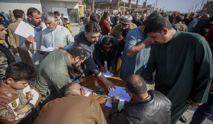 Supporters of the Shiite cleric Muqtada al-Sadr sign a pledge to stand against homosexuality or LGBTQ, outside a mosque in Kufa, Iraq, Friday, Dec. 2, 2022. Al-Sadr who announced his withdrawal from politics four months ago has broken a period of relative silence to launch an anti-LGBTQ campaign. (AP Photo/Anmar Khalil)