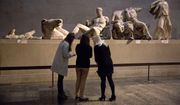 Women stand by a marble statue of a naked youth thought to represent Greek god Dionysos, center, from the east pediment of the Parthenon, on display during a media photo opportunity to promote a forthcoming exhibition on the human body in ancient Greek art at the British Museum in London, Thursday, Jan. 8, 2015. The British Museum has pledged not to dismantle its collection following a report that the institution’s chairman has held secret talks with Greece’s prime minister over the return of the Parthenon Sculptures, also known as the Elgin Marbles. (AP Photo/Matt Dunham, File)