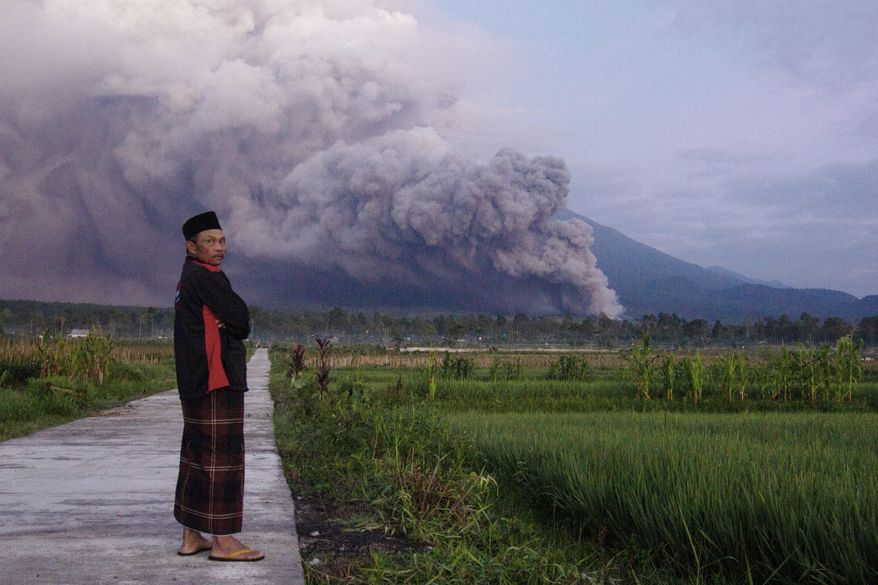 A man looks on as Mount Semeru releases volcanic materials during an eruption on Sunday, Dec. 4, 2022 in Lumajang, East java, Indonesia. Indonesia’s highest volcano on the country’s most densely populated island of Java erupted Sunday. (AP Photo)