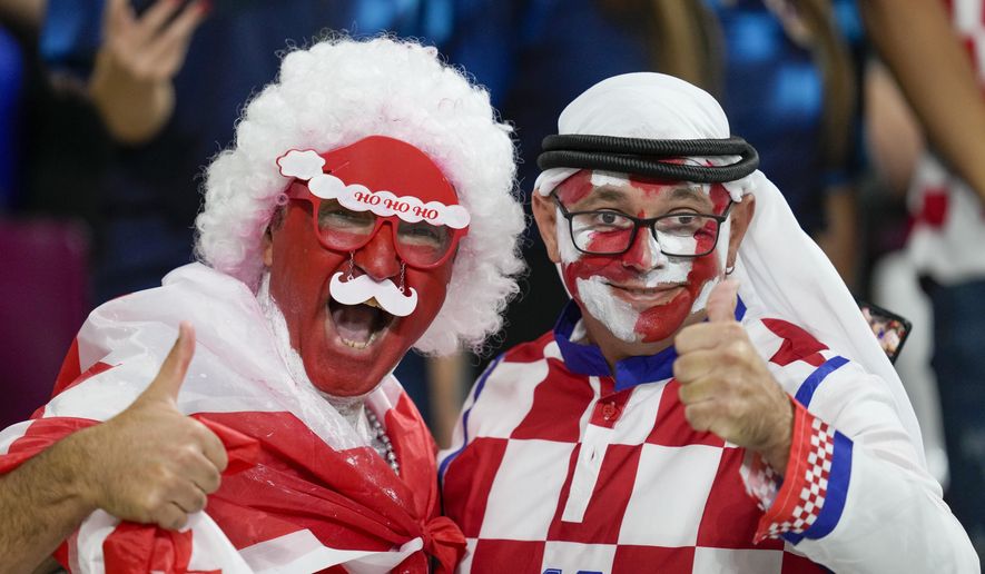 FILE - Croatia and Canada fans cheer ahead of the World Cup group F soccer match between Croatia and Canada, at the Khalifa International Stadium in Doha, Qatar, Sunday, Nov. 27, 2022.  At a World Cup that has become a political lightning rod, it comes as no surprise that soccer fans’ sartorial style has sparked controversy. At the first World Cup in the Middle East, fans from around the world have refashioned traditional Gulf Arab headdresses and thobes. (AP Photo/Darko Vojinovic, File)