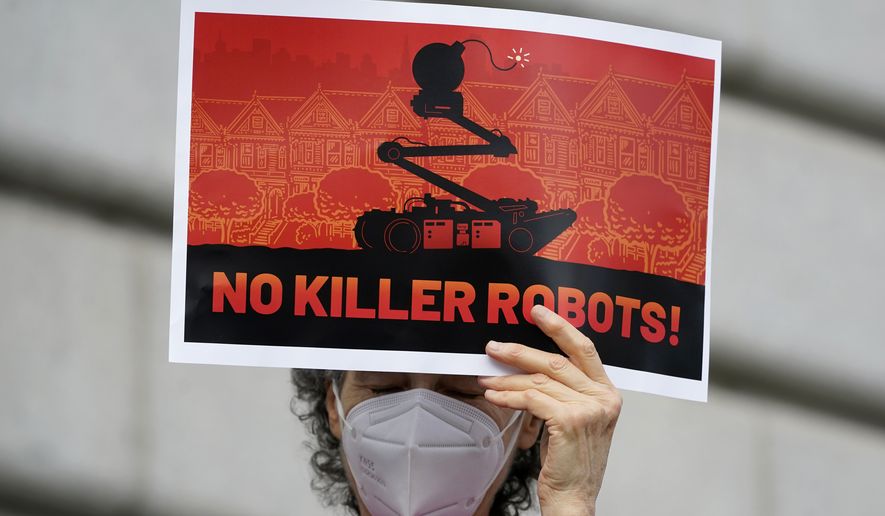 A woman holds up a sign while taking part in a demonstration about the use of robots by the San Francisco Police Department outside of City Hall in San Francisco, Monday, Dec. 5, 2022. The unabashedly liberal city of San Francisco became the unlikely proponent of weaponized police robots this week after supervisors approved limited use of the remote-controlled devices, addressing head-on an evolving technology that has become more widely available even if it is rarely deployed to confront suspects. (AP Photo/Jeff Chiu)