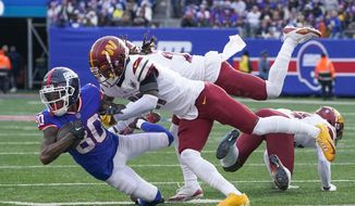 New York Giants&#39; Richie James, left, is tackled by Washington Commanders&#39; defenders during the first half of an NFL football game, Sunday, Dec. 4, 2022, in East Rutherford, N.J. (AP Photo/John Minchillo) **FILE**