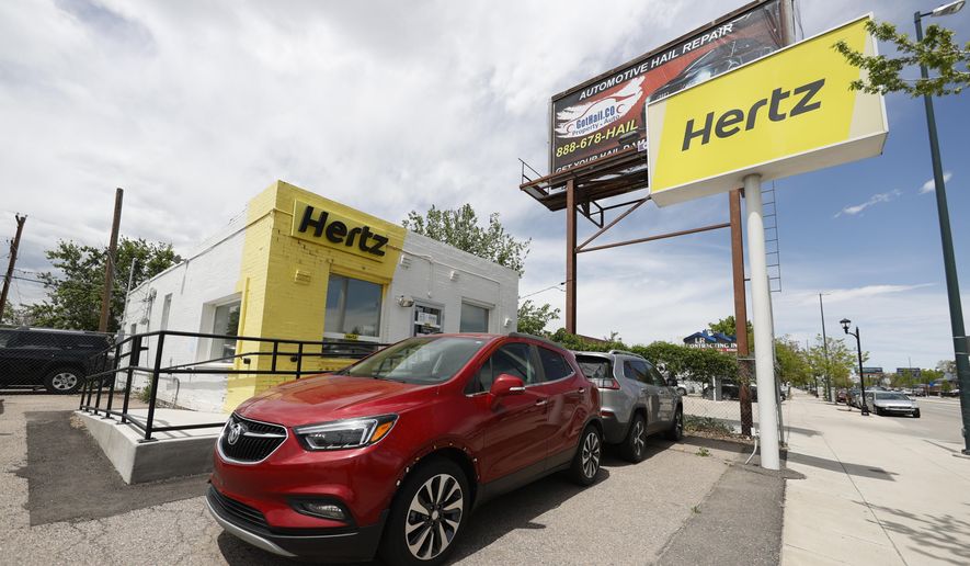 This May 23, 2020, photo shows rental vehicles parked outside a closed Hertz car rental office in south Denver. Hertz says it will pay approximately $168 million by the end of the year to settle the majority of the lawsuits brought against the rental car company by some of its customers who were wrongly accused of stealing cars they had rented. In April Hertz CEO Stephen Scherr, who took over the role in February, said that he was working to fix a glitch in the company’s systems that led to the incidents. (AP Photo/David Zalubowski, file)