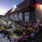 Mourners gather outside Club Q to visit a memorial, which has been moved from a sidewalk outside of police tape that was surrounding the club, on Friday, Nov. 25, 2022, in Colorado Spring, Colo. The suspect accused of entering the gay nightclub clad in body armor and opening fire with an AR-15-style rifle, killing five people and wounding 17 others, is set to appear in court again Tuesday, Dec. 6 to learn what charges prosecutors will pursue in the attack, including possible hate crime counts. (Parker Seibold/The Gazette via AP, File)