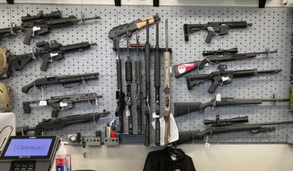 Firearms are displayed at a gun shop in Salem, Ore., on Feb. 19, 2021. A federal judge in Portland, Ore., ruled Tuesday, Dec. 6, 2022, that a new voter-passed ban on high-capacity gun magazines can go into effect Thursday, Dec. 8, but placed a 30-day hold on a permit-to-purchase requirement after local and state law enforcement agencies said they could not have a permitting system ready in time. (AP Photo/Andrew Selsky, File)