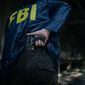 FBI agent holding a gun in his hand, rear view. File photo credit: Shutterstock