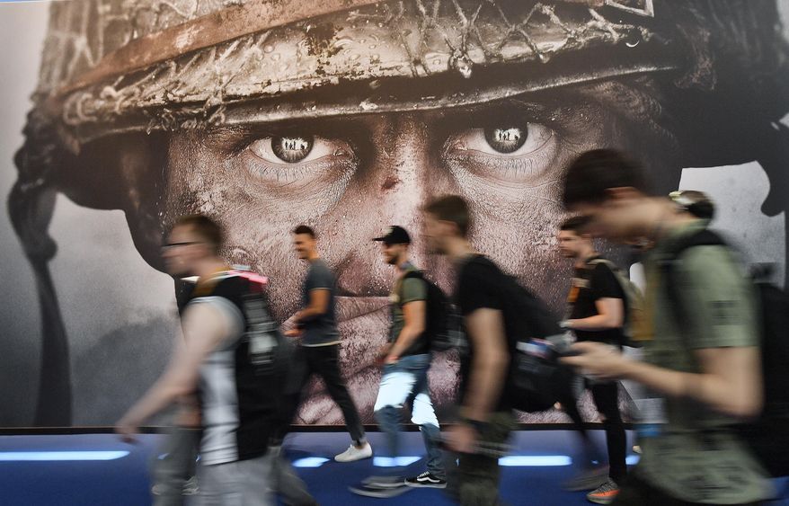 Visitors passing an advertisement for the video game &#x27;Call of Duty&#x27; at the Gamescom fair for computer games in Cologne, Germany, Tuesday, Aug. 22, 2017. Microsoft says it struck a deal to make the hit video game Call of Duty available on Nintendo for 10 years when its $69 billion purchase of game maker Activision Blizzard goes through. The announcement Wednesday, Dec. 7, 2022 is an apparent attempt to fend off objections from rival Sony.  (AP Photo/Martin Meissner, File)