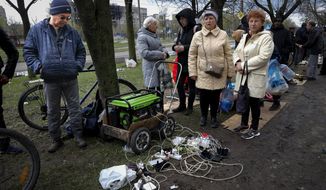 Local residents gather near a generator to charge their mobile devices in an area controlled by Russian-backed separatist forces in Mariupol, Ukraine, Friday, April 22, 2022. When Russian forces two months ago launched a military campaign against infrastructure in Ukraine, it opened an urgent second front far from the contact line: Along power lines, water mains, and heating systems, and in places like homes, schools, offices and churches. (AP Photo/Alexei Alexandrov, File)