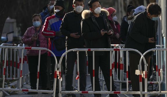 Residents wait in line for their routine COVID-19 test at a coronavirus testing site although authorities start easing some of the anti-virus controls in Beijing, Wednesday, Dec. 7, 2022. China has announced new measures rolling back COVID-19 restrictions, including limiting lockdowns and testing requirements. (AP Photo/Andy Wong)