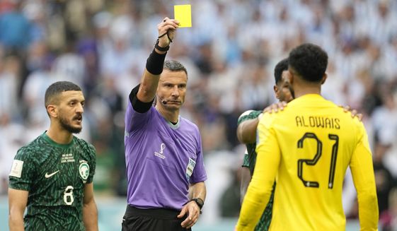 Referee Slavko Vincic of Slovenia, centre, show a yellow card to Saudi Arabia&#x27;s goalkeeper Mohammed Al-Owais during the World Cup group C soccer match between Argentina and Saudi Arabia at the Lusail Stadium in Lusail, Qatar, Tuesday, Nov. 22, 2022. (AP Photo/Ebrahim Noroozi)