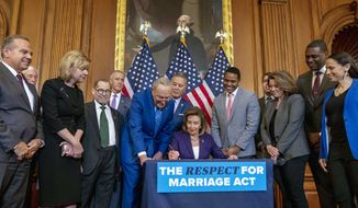 House Speaker Nancy Pelosi of Calif., accompanied by Senate Majority Leader Sen. Chuck Schumer of N.Y., center left, and other members of Congress, signs the H.R. 8404, the Respect For Marriage Act, on Capitol Hill in Washington, Thursday, Dec. 8, 2022. (AP Photo/Andrew Harnik)