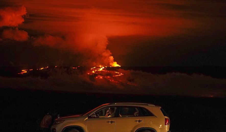 A man talks on a phone in his car alongside Saddle Road as the Mauna Loa volcano erupts Wednesday, Nov. 30, 2022, near Hilo, Hawaii. The world&#39;s largest volcano continues to erupt but scientists say lava is no longer feeding the flow front that has been creeping toward a crucial highway. That means the flow isn&#39;t advancing and is no longer an imminent threat to the road that connects the east and west sides of the Big Island. (AP Photo/Gregory Bull, File)
