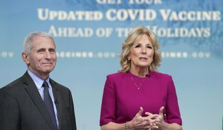 First lady Jill Biden, standing with, Dr. Anthony Fauci, the top U.S. infectious disease expert, speaks during the opening remarks of a virtual White House town hall in the South Court Auditorium on the White House complex in Washington, Friday, Dec. 9, 2022, on getting an updated COVID-19 vaccine this holiday season, especially for Americans ages 50 and older. (AP Photo/Susan Walsh)