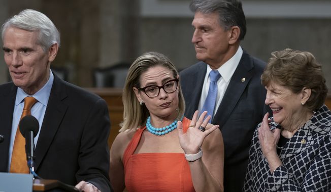 Sen. Kyrsten Sinema, D-Ariz., center, gestures during a news conference at the Capitol in Washington, Wednesday, July 28, 2021, while working on a bipartisan infrastructure bill with, from left, Sen. Rob Portman, R-Ohio, Sen. Joe Manchin, D-W.Va., and Sen. Jeanne Shaheen, D-N.H. Though elected as a Democrat, Sinema announced Friday, Dec. 9, that she has registered as an independent, but she does not plan to caucus with Republicans, ensuring Democrats will retain their narrow majority in the Senate. (AP Photo/J. Scott Applewhite) **FILE**