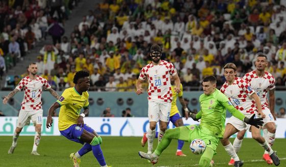 Brazil&#39;s Vinicius Junior, left, tries to score past Croatia&#39;s goalkeeper Dominik Livakovic who makes a save during the World Cup quarterfinal soccer match between Croatia and Brazil, at the Education City Stadium in Al Rayyan, Qatar, Friday, Dec. 9, 2022. (AP Photo/Martin Meissner)
