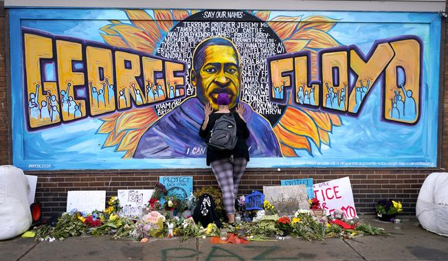 Damarra Atkins pays respect to George Floyd at a mural at George Floyd Square in Minneapolis, April 23, 2021. Minneapolis will buy the boarded-up Speedway gas station at George Floyd Square, the City Council decided unanimously on Thursday, Dec. 8, 2022. The area has become a protest site since Floyd, a Black man, was killed there by a white police officer in May 2020, sparking a national reckoning on racial injustice. (AP Photo/Julio Cortez, File)