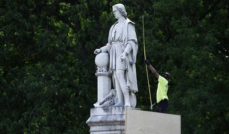 A city worker measures the statue of Christopher Columbus at Marconi Plaza in Philadelphia, June 16, 2020. A judge ruled Friday, Dec. 9, 2022, that Philadelphia must remove the plywood box it placed over the statue after 2020 protests over racial injustice. (AP Photo/Matt Slocum, File)