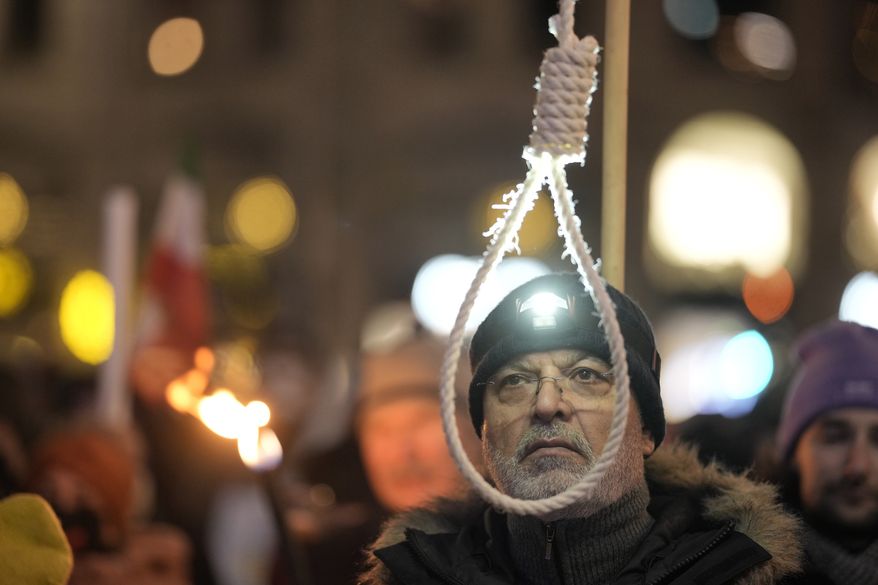 An Iranian protester holds a gallow during a torchlight procession for the Nobel Peace Prize laureates, in front of the Grand Hotel in Oslo, Norway, Saturday, Dec. 10, 2022. This year's Nobel Peace Prize was shared by jailed Belarus rights activist Ales Bialiatski, the Russian group Memorial and the Center for Civil Liberties in Ukraine. The prize was seen as a strong rebuke to the authoritarian rule of Putin. (AP Photo/ Markus Schreiber)