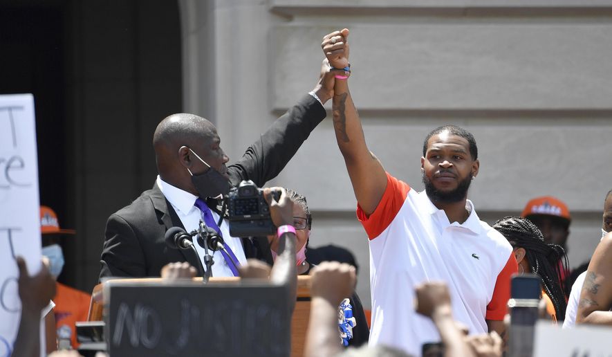 Attorney Benjamin Crump, left, holds up the hand of Kenneth Walker during a rally on the steps of the Kentucky State Capitol in Frankfort, Ky., on June 25, 2020. Walker, the boyfriend of Breonna Taylor who fired a shot at police as they burst through Taylor&#x27;s door the night she was killed, has settled two lawsuits against the city of Louisville, his attorneys said Monday, Dec. 12, 2022. (AP Photo/Timothy D. Easley, File)