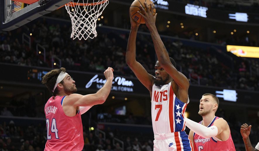 Brooklyn Nets forward Kevin Durant (7) grabs the rebound against Washington Wizards forward Corey Kispert (24) and center Kristaps Porzingis (6) during the first half of an NBA basketball game, Monday, Dec. 12, 2022, in Washington. (AP Photo/Nick Wass)