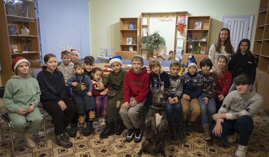 Children traumatized by the war pose for photo with an American pit bull terrier &amp;quot;Bice&amp;quot; in the Center for Social and Psychological Rehabilitation in Boyarka close Kyiv, Ukraine, Wednesday, Dec. 7, 2022. Bice is an American pit bull terrier with an important and sensitive job in Ukraine — comforting children traumatized by the war. The Center for Social and Psychological Rehabilitation is a state-operated community center where a group of people is trying to help those who have experienced trauma after the Feb. 24 Russian invasion, and now they are using dogs like Bice to give comfort. (AP Photo/Vasilisa Stepanenko)