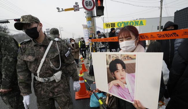 A fan waits for K-pop band BTS&#x27;s member Jin to arrive before he enters the army to serve near an army training center in Yeoncheon, South Korea, Tuesday, Dec. 13, 2022. Jin, the oldest member of K-pop supergroup BTS, was set to enter a frontline South Korean boot camp Tuesday to start his 18 months of mandatory military service, as fans gathered near the base to say goodbye to their star. (AP Photo/Ahn Young-joon)