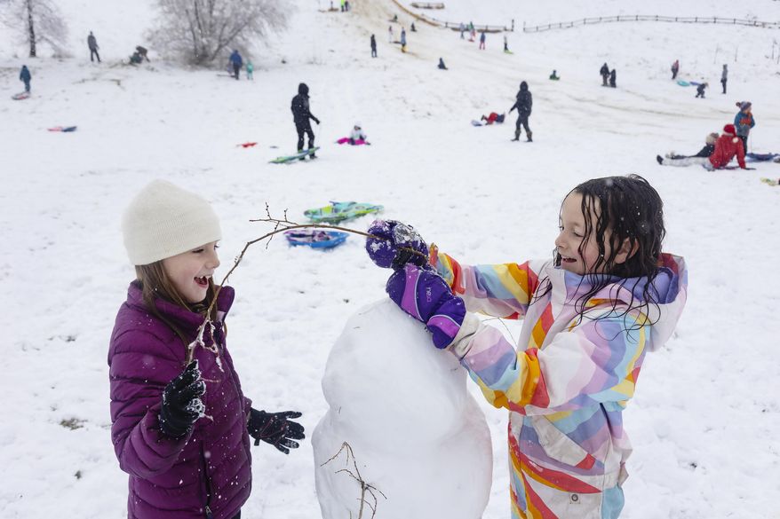 Friends Addie Palmer, 7, left, and Esther Roghaar, 7, right, use tree branches to make arms and even hair on their snowman at Camel's Back Park in Boise, Idaho, on Monday, Dec. 12, 2022. The National Weather Service reported 2.5 inches of snow accumulation overnight from their location at the Boise Airport. No more snow is in the forecast for the Boise area this week, but temperatures are expected to drop to as low as 6 degrees by Saturday night. (Sarah A. Miller/Idaho Statesman via AP)