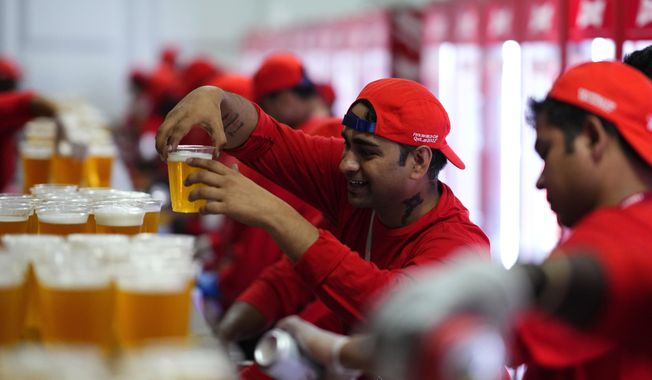 FILE - Staff member holds a beer at a fan zone ahead of the FIFA World Cup, in Doha, Qatar Saturday, Nov. 19, 2022. (AP Photo/Petr Josek, File)