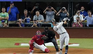 New York Yankees&#39; Aaron Judge connects for a solo home run, his 62nd of the season, off of Texas Rangers starting pitcher Jesus Tinoco as Texas Rangers catcher Sam Huff and umpire Randy Rosenberg look on in the first inning of the second baseball game of a doubleheader in Arlington, Texas, Oct. 4, 2022. (AP Photo/Tony Gutierrez, File)