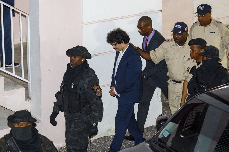 Samuel Bankman-Fried, center, is escorted out of the Magistrate Court building the day after his arrest in Nassau, Bahamas, Tuesday, Dec. 13, 2022. The U.S. government charged Bankman-Fried, the founder and former CEO of cryptocurrency exchange FTX, with a host of financial crimes on Tuesday, alleging he intentionally deceived customers and investors to enrich himself and others, while playing a central role in the company's multibillion-dollar collapse. (Austin Fernander/The Tribune Bahamas via AP)