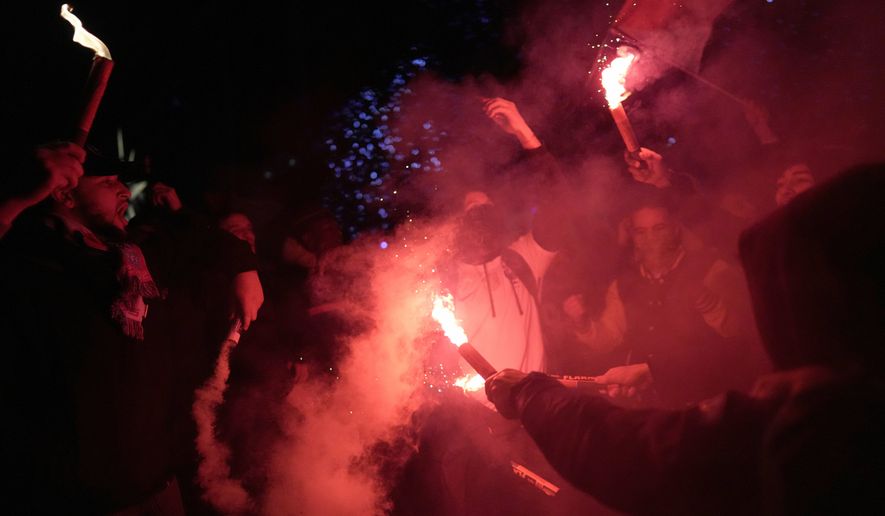 Supporters of France celebrate with flares next to the Arc de Triomphe and the Champs Elysees avenue at the end of the World Cup semifinal soccer match between France and Morocco, in Paris, Wednesday, Dec. 14, 2022. (AP Photo/Thibault Camus)