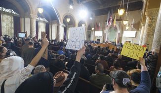 Protesters hold signs and shout slogans during the Los Angeles City Council meeting Tuesday, Dec. 13, 2022 in Los Angeles. A small group of protesters is chanting throughout the meeting calling for the resignations of Councilman Kevin de Leon. (AP Photo/Ringo H.W. Chiu)