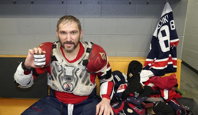 Washington Capitals&#x27; Alex Ovechkin holds his 798, 799, and 800th career goal pucks in the locker room next to hats collected for his hat trick after an NHL hockey game against the Chicago Blackhawks Tuesday, Dec. 13, 2022, in Chicago. (AP Photo/Charles Rex Arbogast) **FILE**