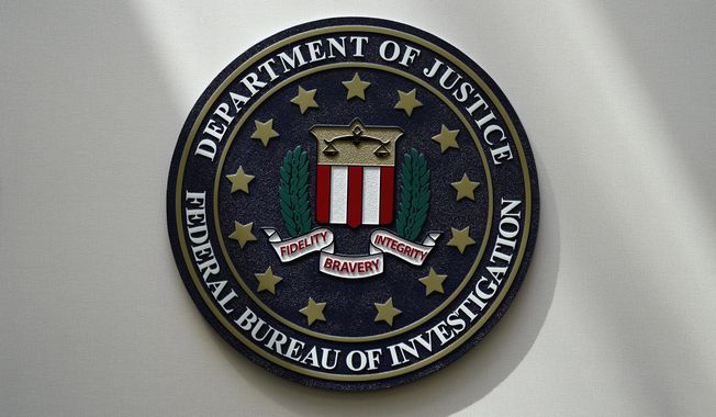 An FBI seal is seen on a wall on Aug. 10, 2022, in Omaha, Neb. A hacker who reportedly posed as the CEO of a financial institution claims to have obtained access to the more than 80,000-member database of InfraGard, an FBI-run outreach program that shares sensitive information on national security and cybersecurity threats with public officials and private sector individuals who run U.S. critical infrastructure. (AP Photo/Charlie Neibergall, File)