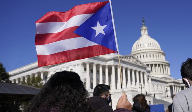 A woman waves the flag of Puerto Rico during a news conference on Puerto Rican statehood on Capitol Hill in Washington, March 2, 2021. The U.S. House has passed a bill that would allow Puerto Rico to hold the first-ever binding referendum on whether to become a state or gain some sort of independence. It is a last-ditch effort that stands little chance of passing the Senate.  (AP Photo/Patrick Semansky, File)