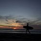 A man is silhouetted against the sky at sunset after coming out of the Pacific Ocean at Mission Beach, Friday, Dec. 16, 2022, in San Diego. (AP Photo/Charlie Riedel) ** FILE **