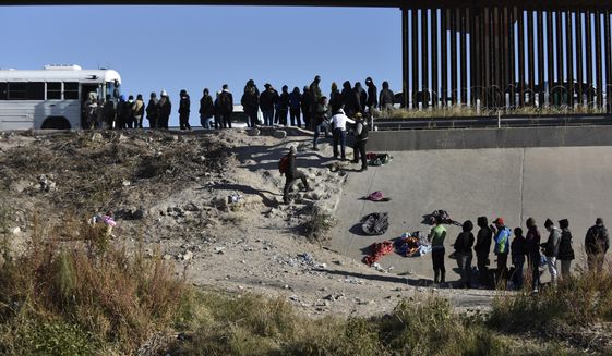 FILE - Migrants wait to get into a U.S. government bus after crossing the border from Ciudad Juarez, Mexico, to El Paso, Texas, Monday, Dec. 12, 2022. The mayor of the Texas border city declared a state of emergency Saturday, Dec. 17 over concerns about the community&#x27;s ability to handle an anticipated influx of migrants across the Southern border. El Paso Mayor Oscar Leeser issued the state of emergency declaration to allow the city to tap into additional resources that are expected to become necessary after Title 42 expulsions end on Dec. 21. (AP Photo/Christian Chavez, File)