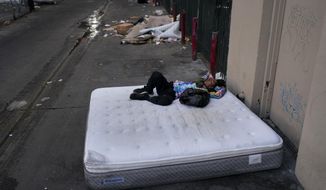 FILE - A homeless man sleeps on a discarded mattress in Los Angeles, Thursday, July 21, 2022. On Sunday, Dec. 18, 2022, Los Angeles Mayor Karen Bass said her administration will start moving homeless people in tent encampments into hotel and motel rooms through a new program that launches on Tuesday. (AP Photo/Jae C. Hong, File)