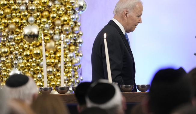 President Joe Biden walks past the White House menorah after speaking during a Hanukkah holiday reception in the Grand Foyer of the White House in Washington, Monday, Dec. 19, 2022. (AP Photo/Susan Walsh)